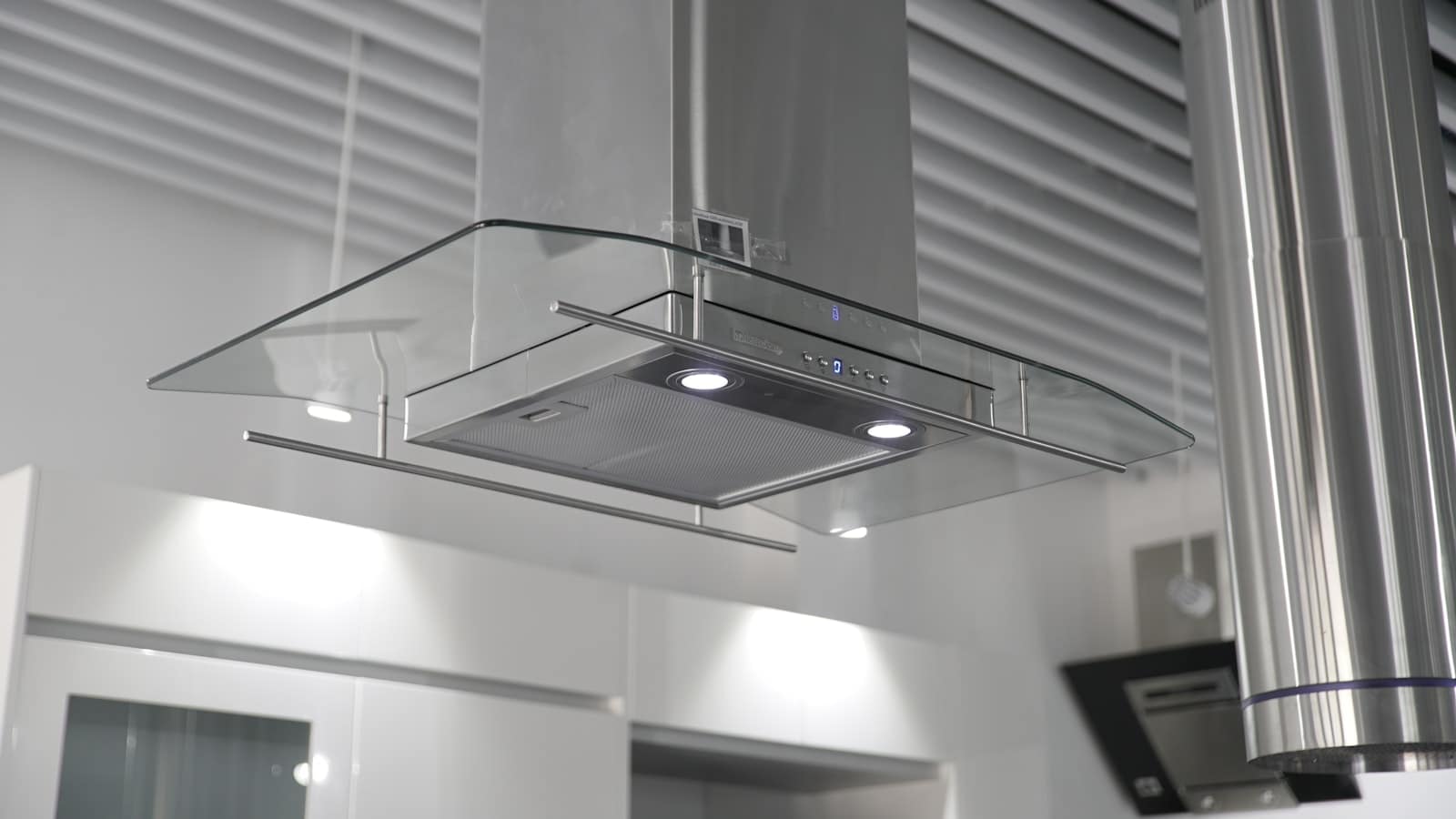 Stainless steel and glass extractor hood above a modern kitchen island