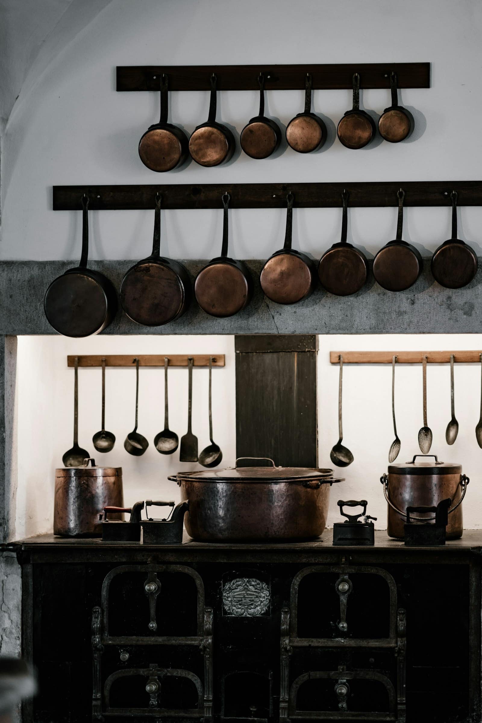 Black cast-iron range cooker with copper pans in a farmhouse kitchen